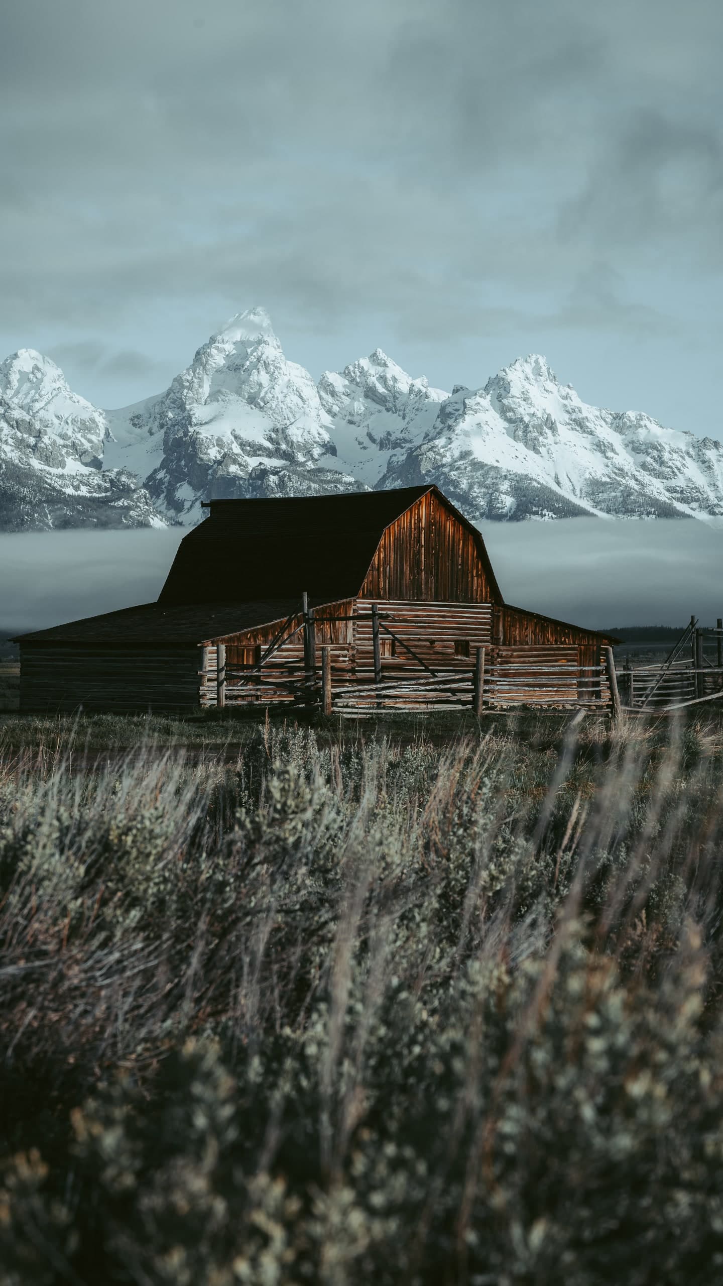 A weathered wooden barn beneath the snow-capped Teton mountains.